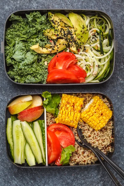 Healthy meal prep containers with quinoa, avocado, corn, zucchini noodles and kale. Takeaway food. Dark background, top view.
