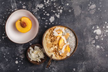 Güler yüzlü chia puding, şeftali, Hindistan cevizi ve granola karanlık backgroud, üstten görünüm üzerinde bir Hindistan cevizi kase kase. Vegan sağlıklı kahvaltı, kavram yeme temiz.