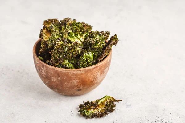 Kale chips in a wooden bowl on white background. Clean eating concept. Go vegan!