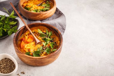 Sarı Hint Vejetaryen mercimek çorbası köri bir ahşap kase, beyaz arka plan, üstten görünüm.