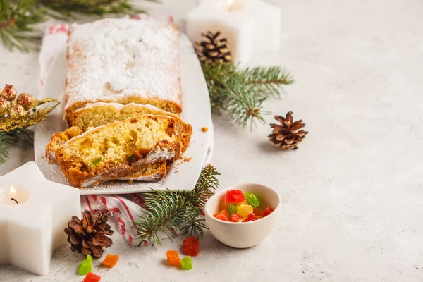 Christmas bread with candied fruits and powdered sugar in Christmas decorations, copy space.