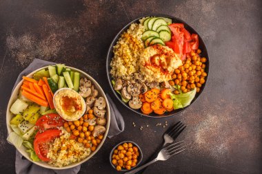 Buda sebze, mantar, bulgur, humus ve pişmiş nohut ile kase. Koyu arka plan, üstten görünüm. Sağlıklı vegan gıda kavramı.
