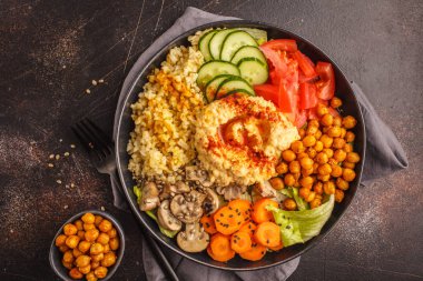 Buda kase sebze, mantar, bulgur, humus ve pişmiş nohut. Koyu arka plan, üstten görünüm. Sağlıklı vegan gıda kavramı.