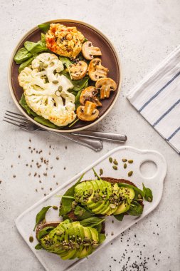 Karnabahar biftek ızgara petrol ve humus ve avokado tost, üstten görünüm. Bitki esaslı diyet kavramı.