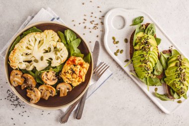 Karnabahar biftek ızgara petrol ve humus ve avokado tost, üstten görünüm. Bitki esaslı diyet kavramı.