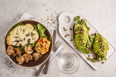 Karnabahar biftek ızgara petrol ve humus ve avokado tost, üstten görünüm. Bitki esaslı diyet kavramı.