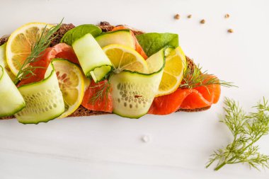 Alabalık (somon) balık sandviç ogerets, çavdar ekmeği ve dereotu ile beyaz bir arka plan üzerine dilimlenmiş.