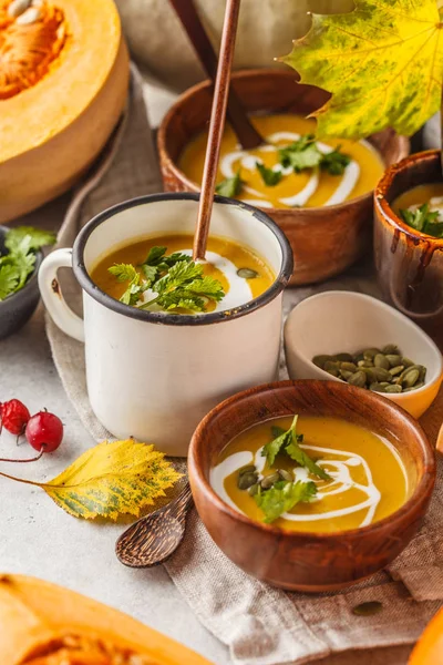 Autumn pumpkin soup puree with cream in cups, the autumn scenery. Healthy vegan food concept. Autumn food concept.