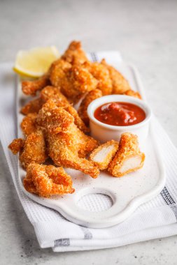 Bir beyaz tahta üzerinde domates soslu kızarmış tavuk.