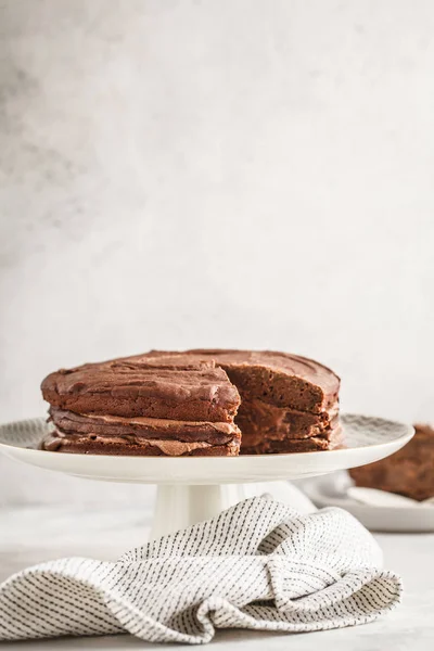 Vegan chocolate cake on a white dish for cake, light background. Healthy vegan food concept.