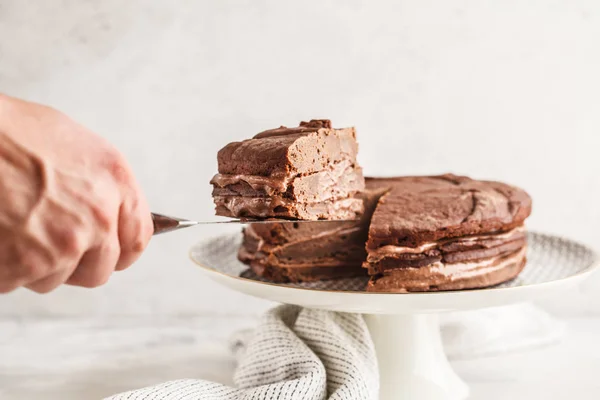 Vegan chocolate cake on a white dish for cake, light background. Healthy vegan food concept.