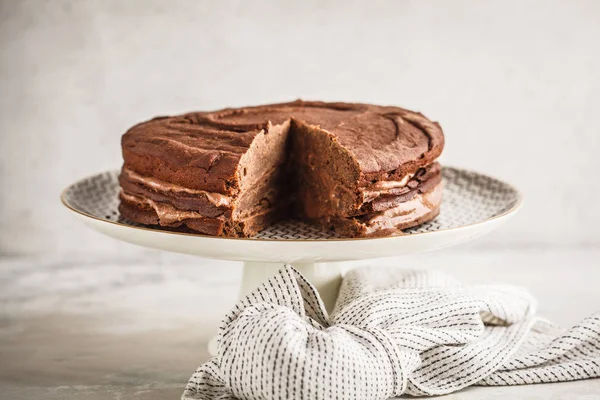 Vegan chocolate cake on a white dish for cake, light background. Healthy vegan food concept.