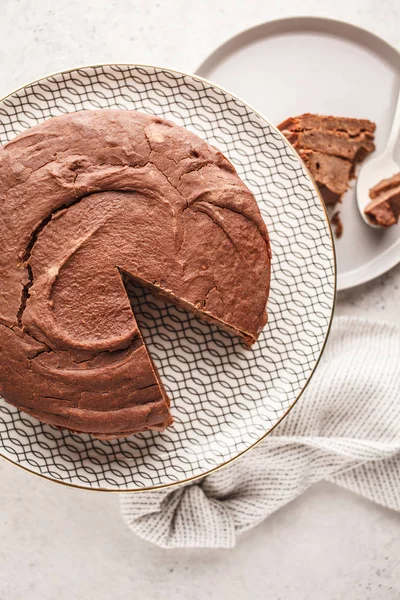 Vegan chocolate cake on a white dish for cake, light background. Healthy vegan food concept.