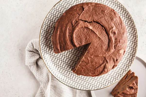 Vegan chocolate cake on a white dish for cake, light background. Healthy vegan food concept.