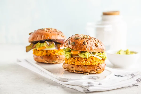 Vegan sweet potato (or pumpkin) burgers on white background. Vegetable burgers, avocado, vegetables and buns. Clean eating, plant based food concept.