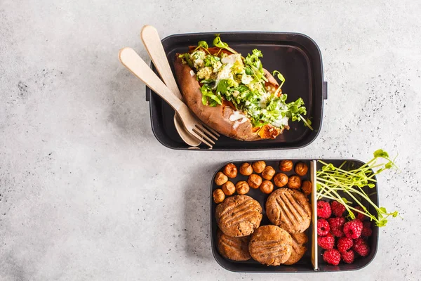 Healthy meal prep containers with quinoa Stuffed Sweet Potatoes, cookies, nuts and berries, overhead shot with copy space.