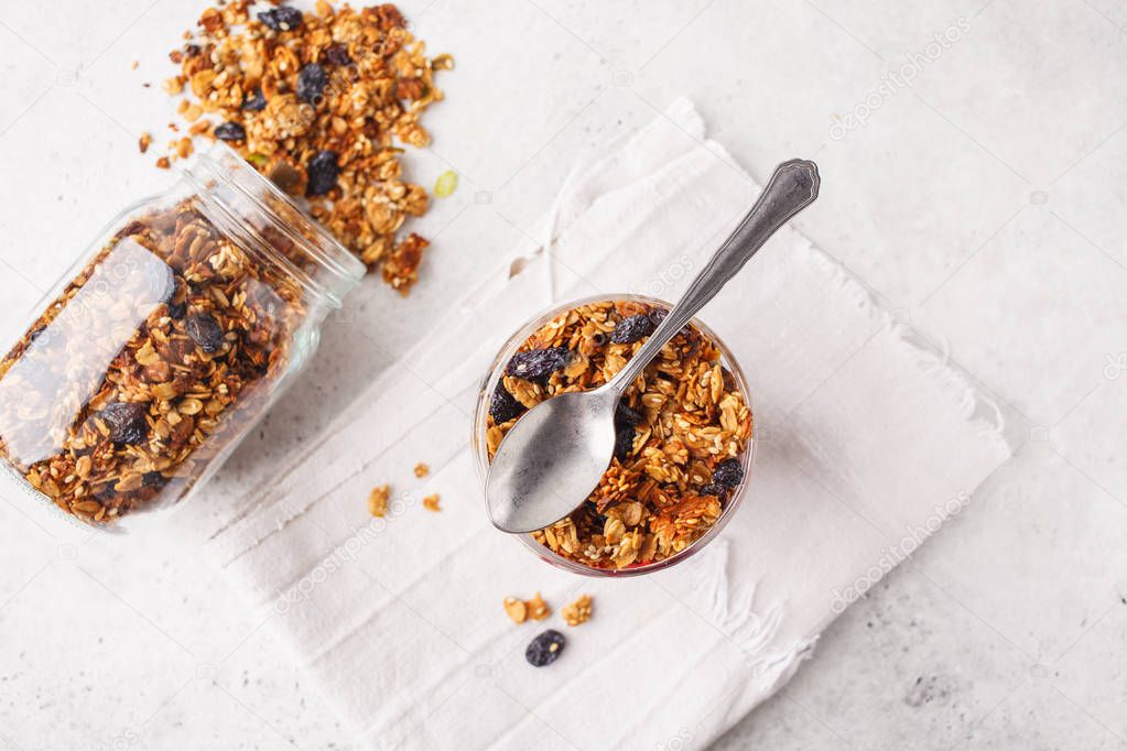 Baked granola with raisins in gray bowl, white backgroundl. Vegan healthy food concept.