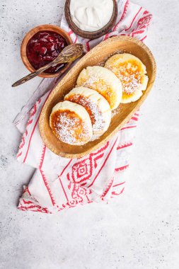 Ekşi krema ve reçel üzerinde beyaz bir arka plan üzerinde ahşap bir kase süzme peynir krep.