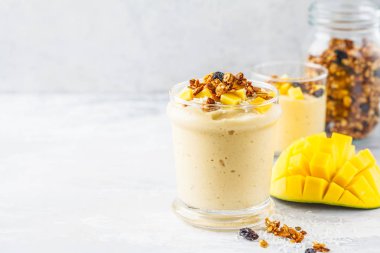 Mango smoothie granola ve bir kavanoz içinde Hindistan cevizi ile. Sağlıklı vegan gıda kavramı.