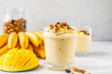 Mango muz smoothie granola ve bir kavanoz içinde Hindistan cevizi ile. Bitki esaslı gıda kavramı.