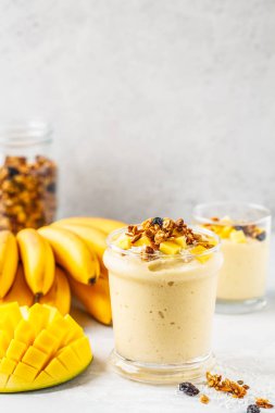 Mango muz smoothie granola ve bir kavanoz içinde Hindistan cevizi ile. Bitki esaslı gıda kavramı.