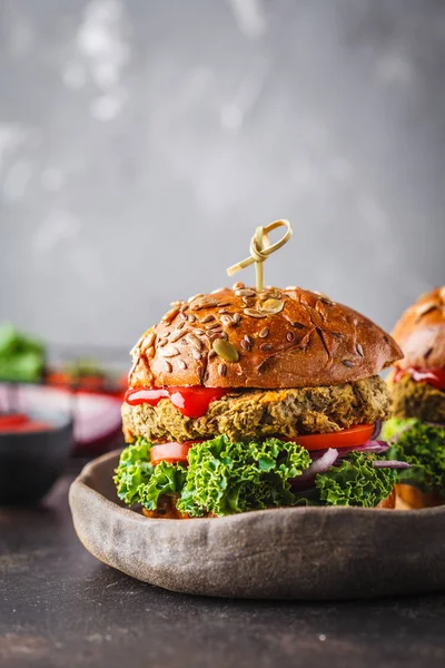 Vegan lentil burgers with kale and tomato sauce on a dark background. Plant based diet cincept.