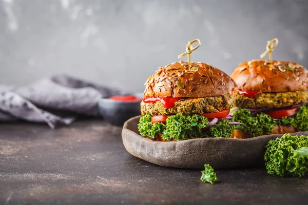 Vegan lentil burgers with kale and tomato sauce on a dark background. Plant based diet cincept.