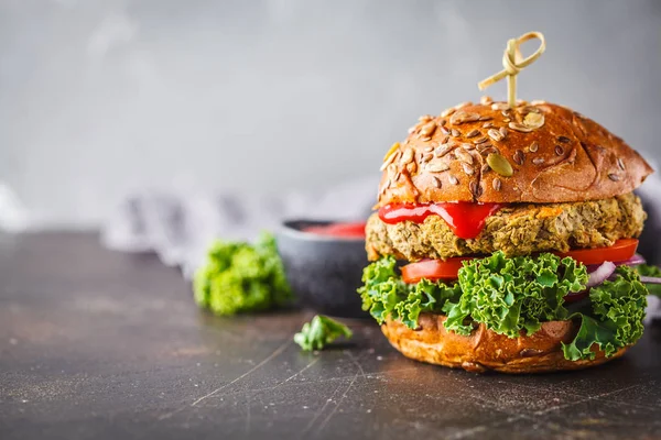 Vegan lentil burgers with kale and tomato sauce on a dark background. Plant based diet cincept.