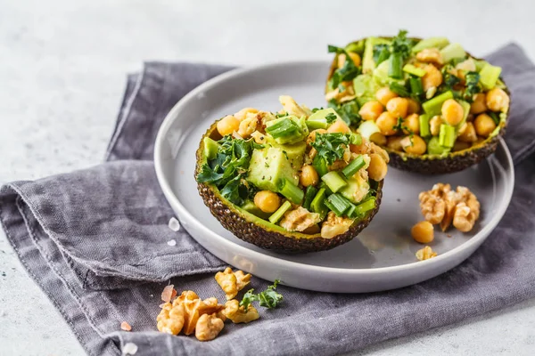 Avocado halves stuffed with avocado, nuts and chickpeas. Plant based diet concept.