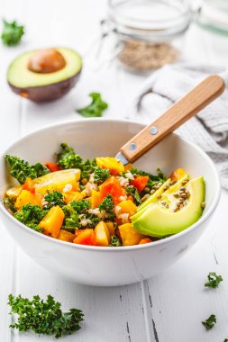 Vegan pirinç, kale, pişmiş kabak, havuç ve beyaz ahşap zemin üzerinde beyaz kase avokado salatası.