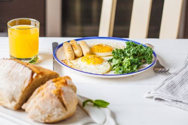 Sahanda yumurta, salata, kekler ve portakal suyu mutfakta beyaz tahta masada kahvaltı servis.