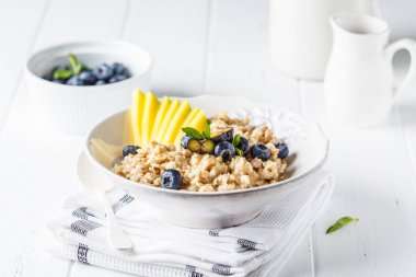 Mango ve yaban mersini, beyaz arka plan ile yulaf lapası.