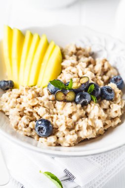 Mango ve yaban mersini, beyaz arka plan ile yulaf lapası.