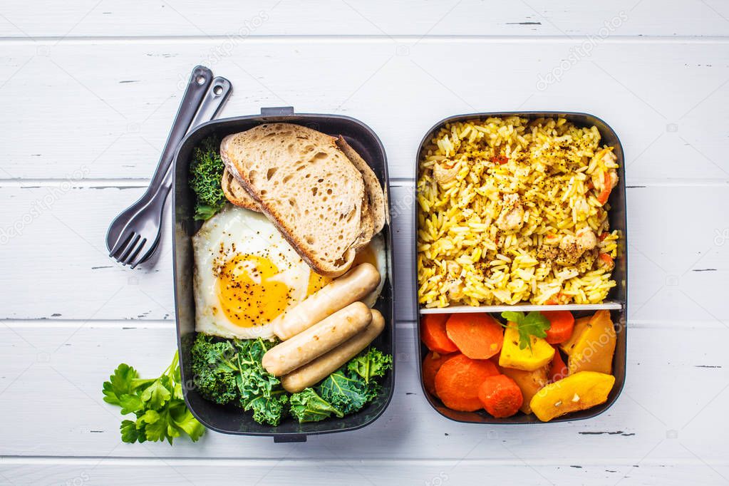 Meal prep containers with rice with chicken, baked vegetables, eggs, sausages and salad for breakfast and lunch overhead shot, copy space, wtite wooden background.