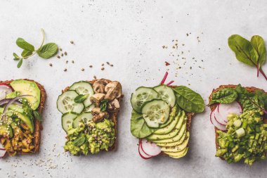 Avokado tost farklı soslar, üstten görünüm, beyaz arka plan ile. Bitki esaslı diyet kavramı.