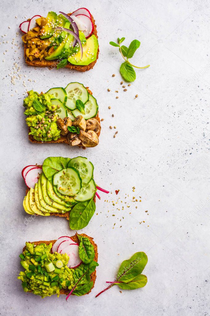 Avocado toasts with different toppings, top view, white background. Plant based diet concept.