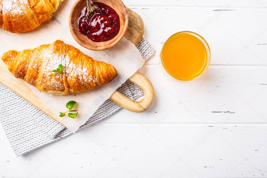 Croissants with berry jam on a white wooden background, top view, copy space.