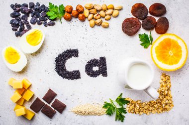 Kalsiyum sağlıklı ürünler kaynakları. Ana sayfa görünümü, gıda arka plan, Ca malzemeler: tahıllar, kuruyemiş, süt ürünleri, turuncu, fındık, yeşil ve beyaz zemin üzerine peynir.