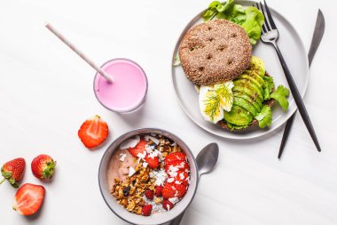 Güzel kahvaltı düz yatıyordu: güler yüzlü kase, avokado tost ve beyaz mermer zemin, üst üzerinde tatlı görüntüleyin. Sevgililer günü kavramı.