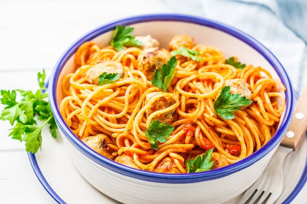 Pasta with turkey meatballs and tomato sauce in a white dish.