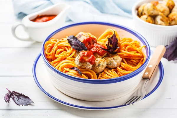 Pasta with turkey meatballs and tomato sauce in a white dish.