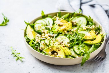 Sağlıklı yeşil salata avokado, salatalık ve roka beyaz tabak içinde. Bitki esaslı diyet kavramı.