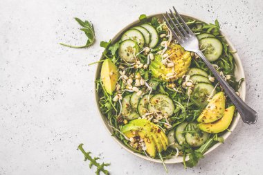 Sağlıklı yeşil salata avokado, salatalık ve roka beyaz tabak içinde. Bitki esaslı diyet kavramı.