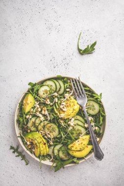 Sağlıklı yeşil salata avokado, salatalık ve roka beyaz tabak içinde. Bitki esaslı diyet kavramı.
