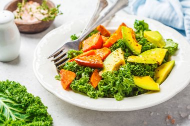 Avokado ve pişmiş tatlı patates sağlıklı yeşil lahana salatası. Göre diyet kavramı bitki, gıda detoks. Üstten görünüm, beyaz arka plan.