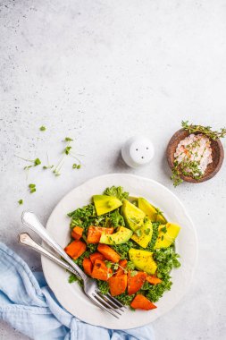 Avokado ve pişmiş tatlı patates sağlıklı yeşil lahana salatası. Göre diyet kavramı bitki, gıda detoks. Üstten görünüm, beyaz arka plan.
