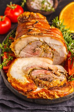 Klasik İtalyan porchetta portakal ile pişmiş. Karanlık bir arka plan üzerinde pişmiş domuz. İtalyan mutfağı kavramı.