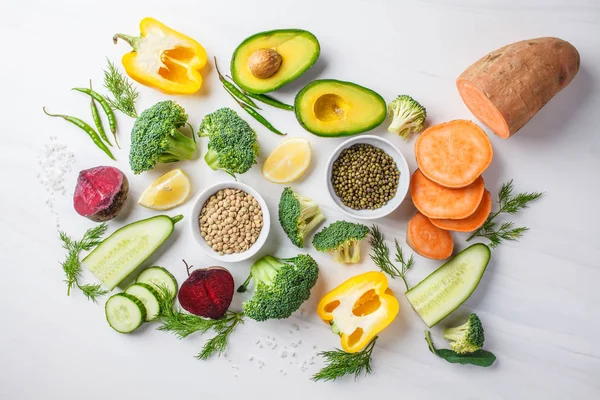 Vegan food background. Balanced food ingredients on a white background, top view. Vegetables, legumes for cooking healthy salad.