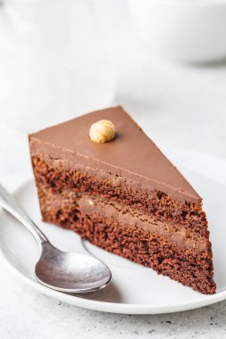 Beyaz tabak, beyaz arka plan üzerinde çikolatalı kek parçası. Vegan tatlı, bitki esaslı gıda kavramı.