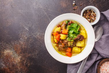 Geleneksel Alman eintopf et, fasulye ve beyaz bir tabakta sebze çorbası. Üstten görünüm, koyu arka plan.